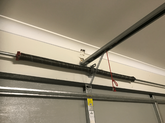 Torsion spring above garage door with opener rail