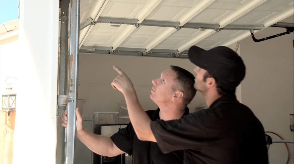 2 people conducting maintenance on a garage door